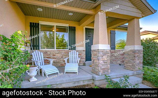Entrance to a home with steps leading tothe porch. Entrance of a home with a pathway and steps leading to the small porch with chairs