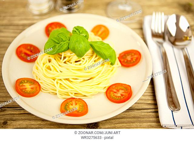 frische leckere Pasta mit Tomaten und Basilikum auf einem Holzbrett