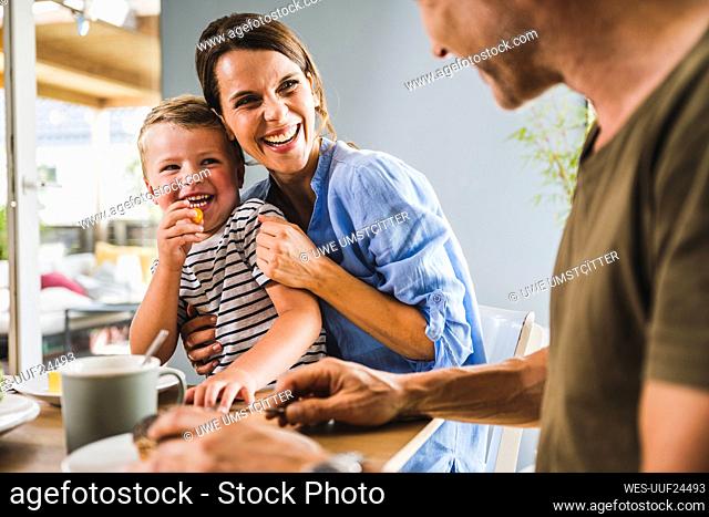 Smiling mother and son looking at father having breakfast at home