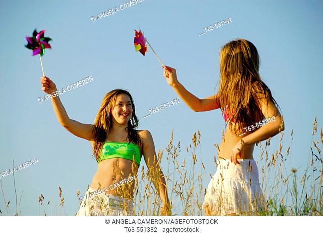 girl 13, girl 18 yrs playing together with pinwheels at the beach