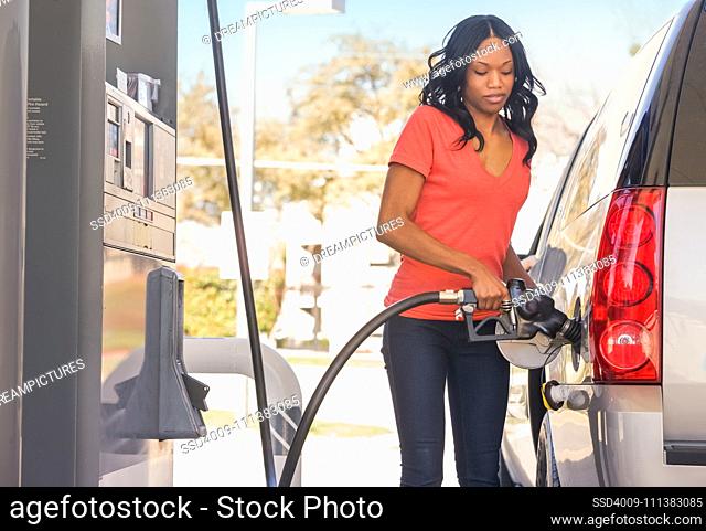 African American woman pumping gas at gas station