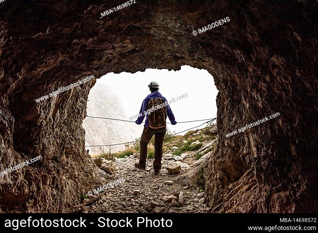 A hiker enjoying the view out of an old military tunnel at Mount Lagazuoi, autonomous province of South Tirol