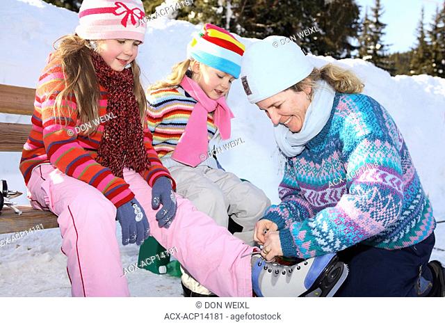 Mother and two daughters getting ready to go ice skating, Silver Star Mountain Resort, Vernon, British Columbia, Canada