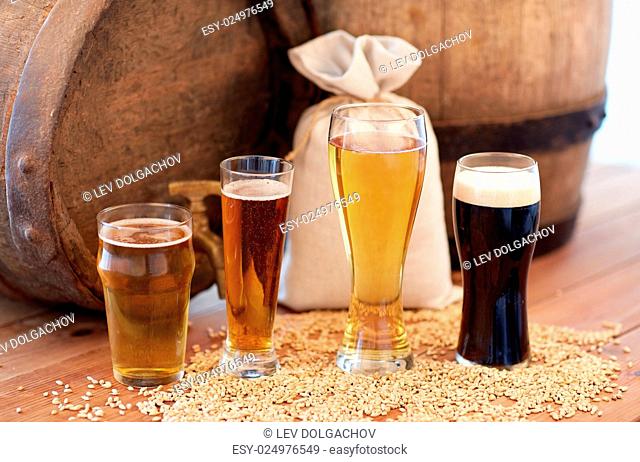 brewery, drinks and alcohol concept - close up of old beer barrel, glasses and bag with malt on wooden table