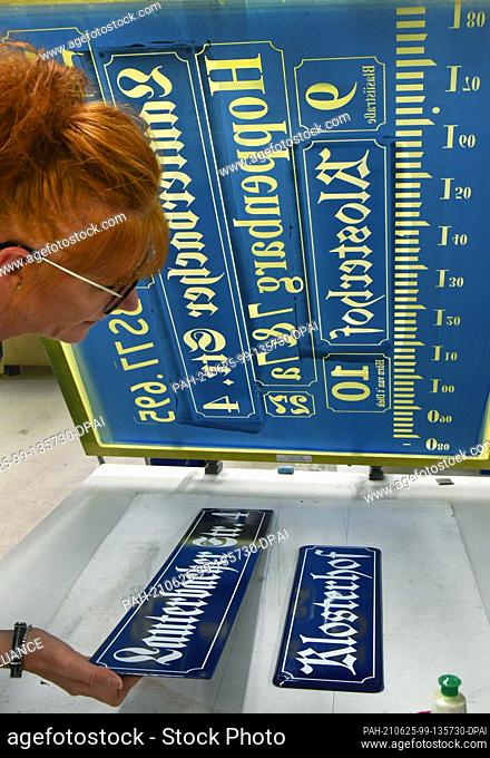 23 June 2021, Saxony, Penig: At Muldenthaler Emaillierwerk GmbH, the head of the sign department, Katrin Engert-Hecht produces signs using the hand screen...