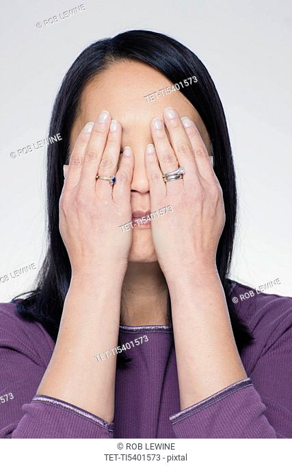 Studio portrait of mature woman covering eyes