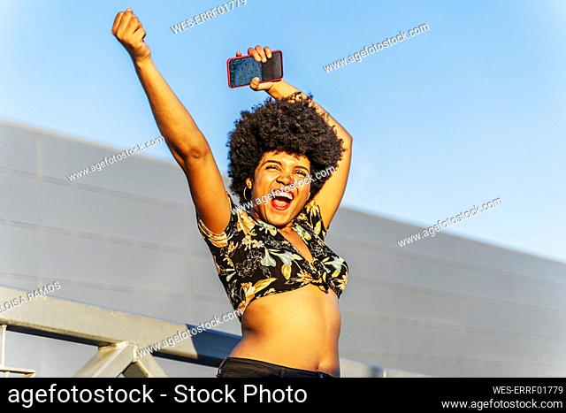 Smiling Afro-American woman with red smartphone