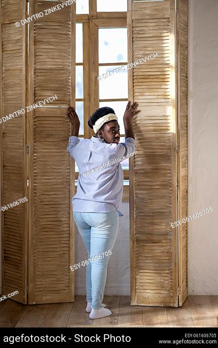 At home. African american woman standing near the window