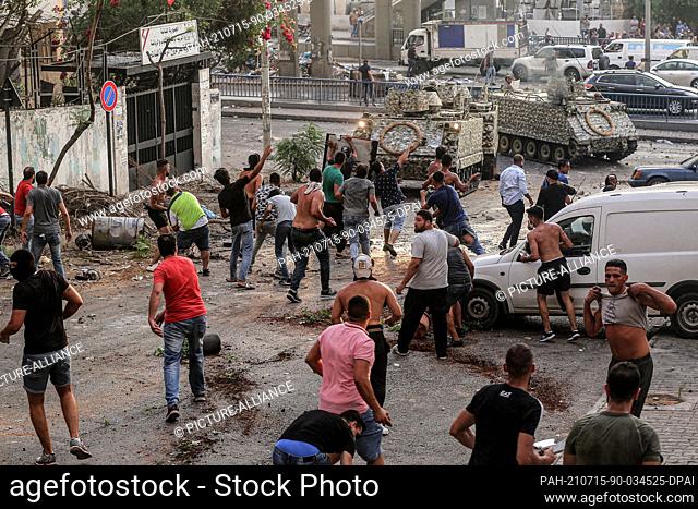 15 July 2021, Lebanon, Beirut: Protesters hurl rocks at Lebanese army armoured personnel carriers (APC) during clashes after Lebanon's Prime Minister-designate...