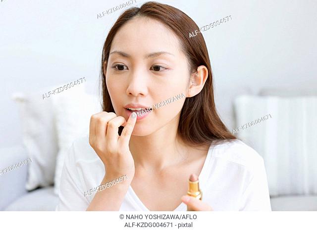 Young attractive Japanese woman doing her make-up at home