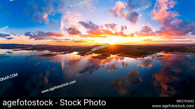 Drone aerial panorama of a lake reservoir of a dam with perfect reflection on the water of the sunset in Sabugal, Portugal