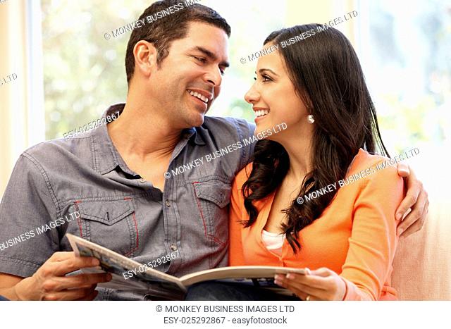 Hispanic couple at home reading magazine