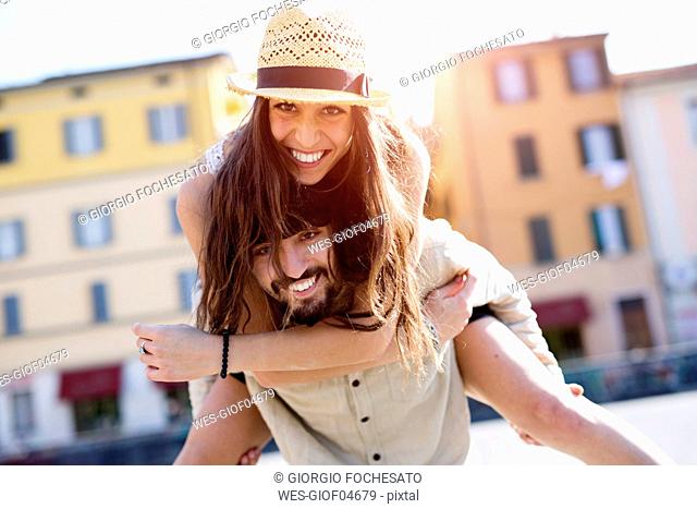 Portrait of happy young man giving his girlfriend a piggyback ride