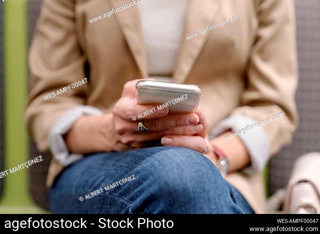 Woman holding mobile phone while sitting at subway station