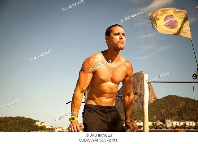 Mid adult man training on parallel bars, Rio De Janeiro, Brazil