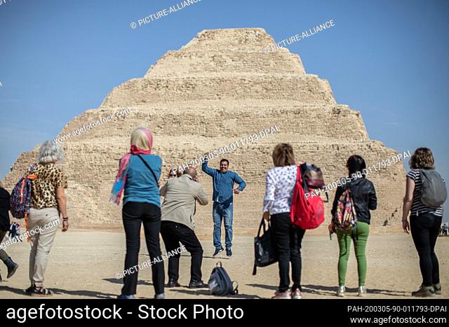 05 March 2020, Egypt, Saqqara: Tourists take souvenir pictures in front of the Pyramid of Djoser in Saqqara outside Cairo