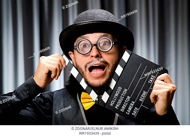Funny man with movie board against curtain