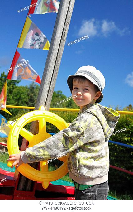 Young captain behind the toy steer wheel