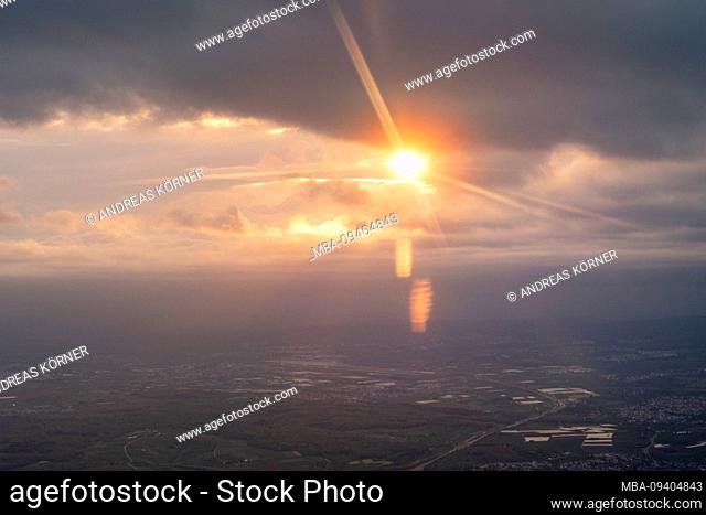 View from the window of an airplane at sunset with impressive light play over southern German landscape