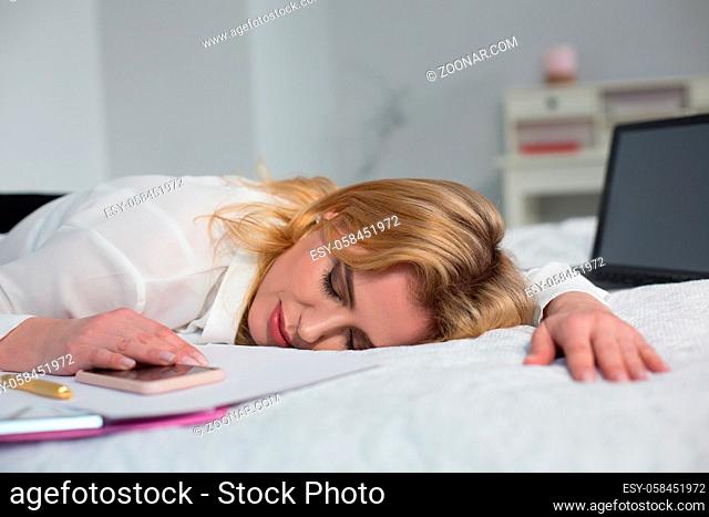 Tired businesswoman fall asleep in bed after long business trip. Isolated on white background