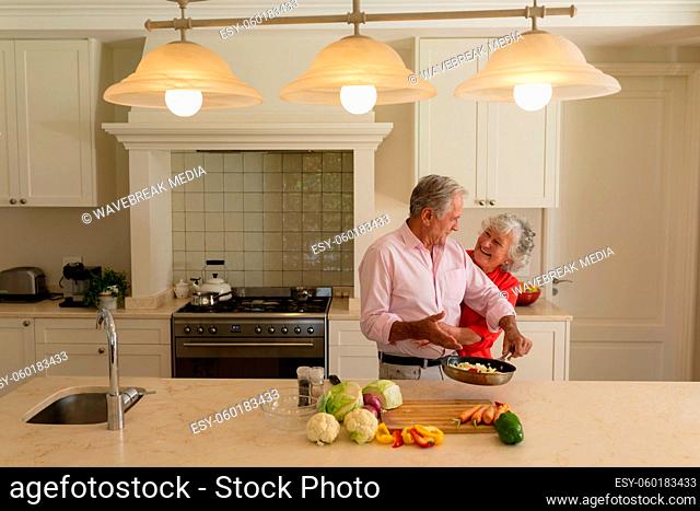 Senior caucasian couple cooking together and smiling in kitchen