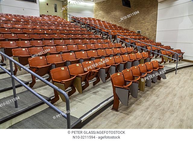 Row of empty chairs, with stairs in the middle, in an auditorium