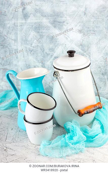 Two white enamel mug, jug blue and white can on light background