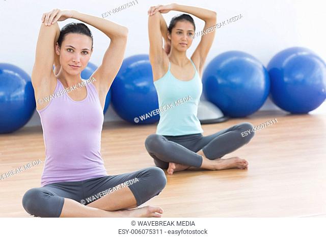 Two women stretching hands in fitness studio