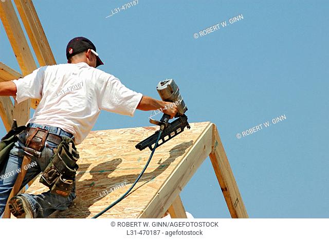 Roofers putting on sub roof of partical board on new home construction with nailguns