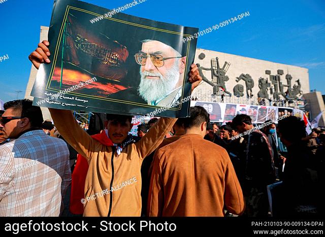 03 January 2021, Iraq, Baghdad: An Iraqi man holds a poster of Iranian supreme leader Ali Khamenei during a protest at Tahrir Square to commemorate the one-year...