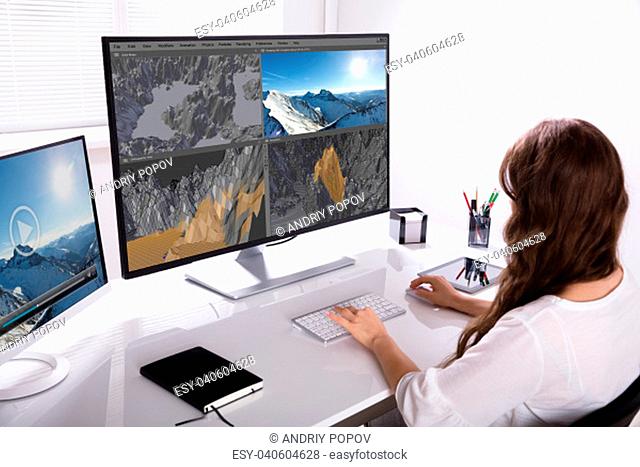 Rear View Of A Woman Working On 3D Landscape On Computer In Office