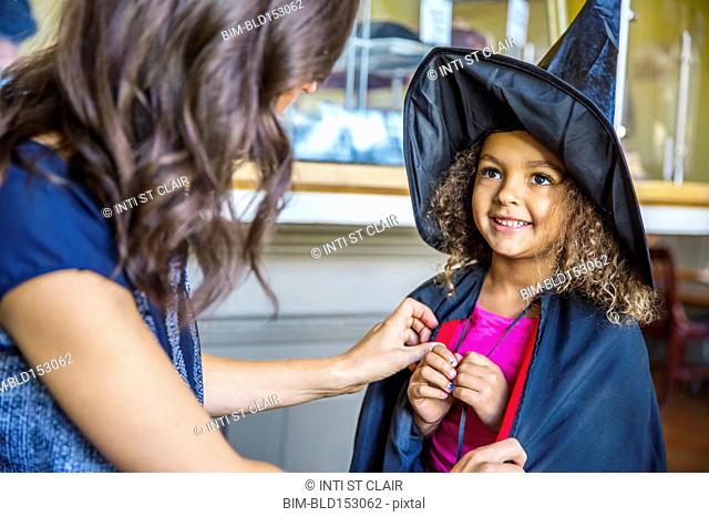 Mother dressing daughter in witch costume