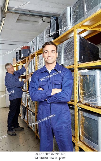 Worker standing with arms crossed in monitor storage of computer recycling plant