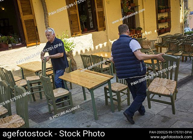 25 May 2020, Greece, Athen: Two men rearrange the tables in a tavern in the Plaka tourist district, as the cafés and restaurants are reopening today