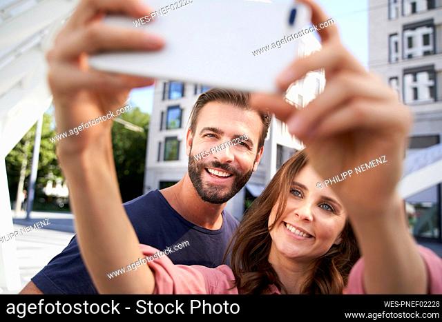 Happy couple taking a selfie in the city