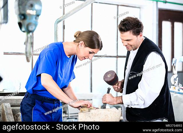 two Stonemasons carving pillar out of stone in workshop