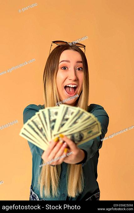 very excited young woman holds cash money in dollar banknotes. Shopping