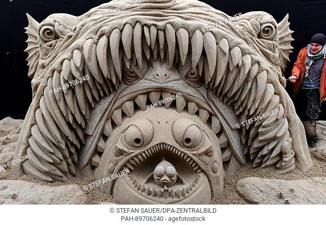 Sculptor Donatan Mockus from Lithuania works on a sculpture of a monster fish at the annual sand sculpture festival in Ahlbeck on Usedom island, Germany