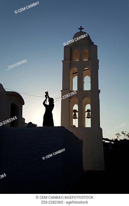 Silhouette of a woman taking photo near the Panagia Kimissis church situated at the cliff in Hora, Folegandros, Cyclades Islands, Greek Islands, Greece, Europe
