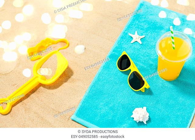 sunglasses, sand toys and juice on beach towel