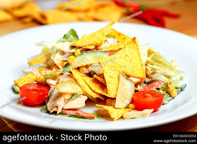 Salad with corn, beans, avocado and nachos. On a white plate, the dish is served in the restaurant. Italian traditional food