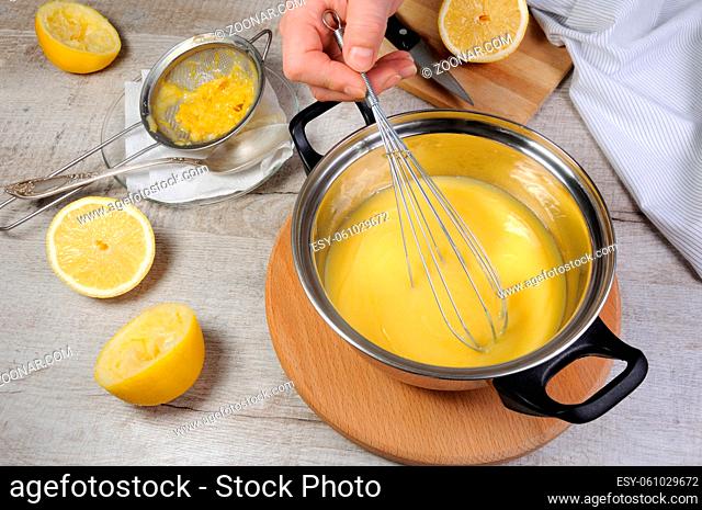 Freshly prepared lemon kurd - custard on fruit juice, in a saucepan whipped with whisk