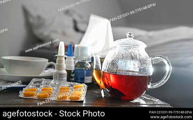 ILLUSTRATION - 29 October 2023, Baden-Württemberg, Stuttgart: Medicines and a pot and cup of tea to fight a cold are placed on a bedside table