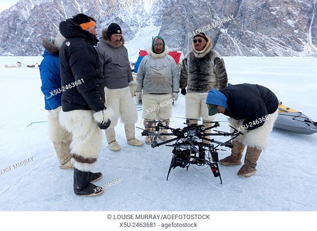 Group of Inuit or Inughiut hunters from Qaanaaq, Greenland at the floe edge in Hvalsund, looking at octocopter drone used for filming 4G, hi definition filming