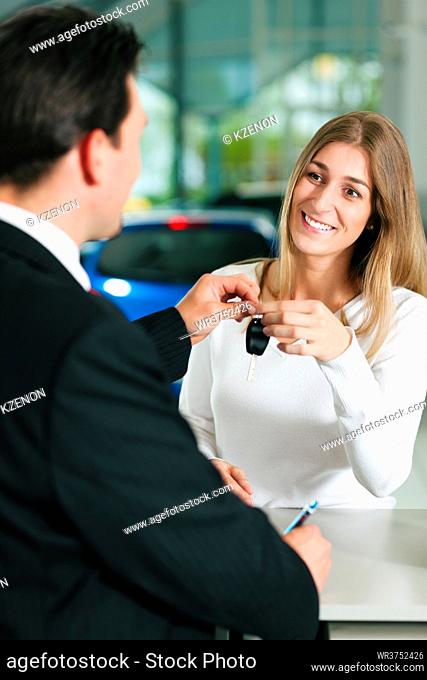 Woman at a car dealership buying an auto, the sales rep giving her the key