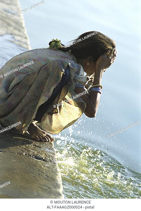 India, Sarkej, girl washing face by river