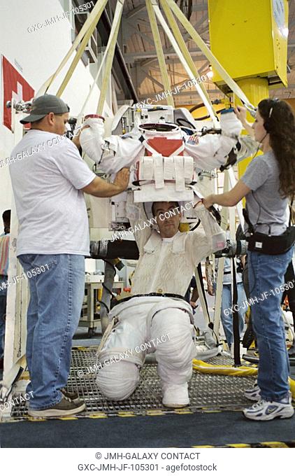 Astronaut Philippe Perrin, STS-111 mission specialist, dons a training version of the Extravehicular Mobility Unit (EMU) space suit prior to being submerged in...