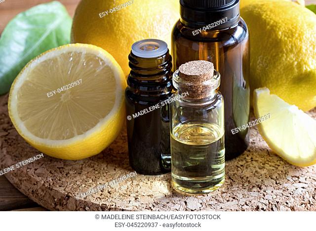 Bottles of lemon essential oil with fresh lemons in the background