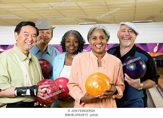 Friends holding bowling balls in bowling alley