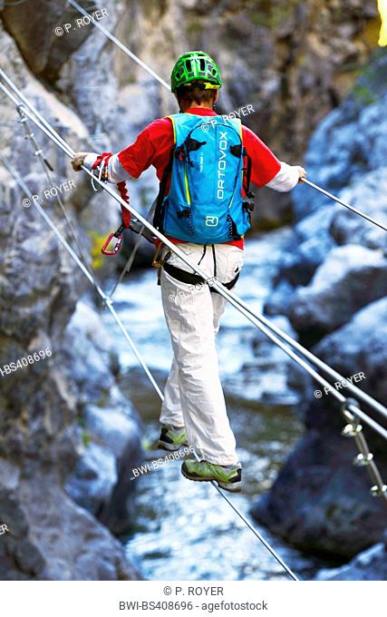 climber crossing the canyon on a suspension bridge, France, Hautes Alpes, Chateau Queyras